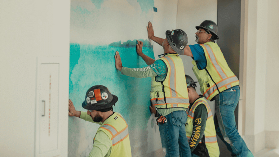 three construction workers install panels on interior wall